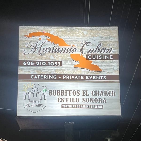 A lighted sign for Marianao Cuban Cuisine and Burritos El Charco Estilo Sonora at night.