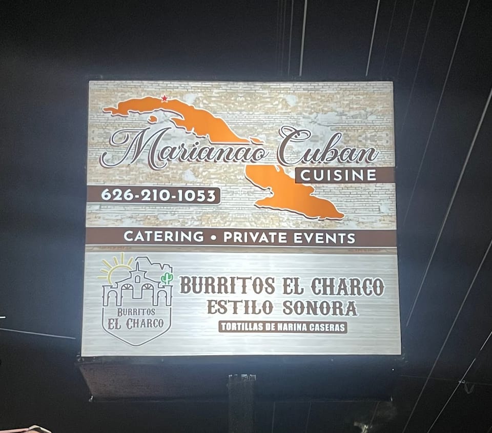 A lighted sign for Marianao Cuban Cuisine and Burritos El Charco Estilo Sonora at night.